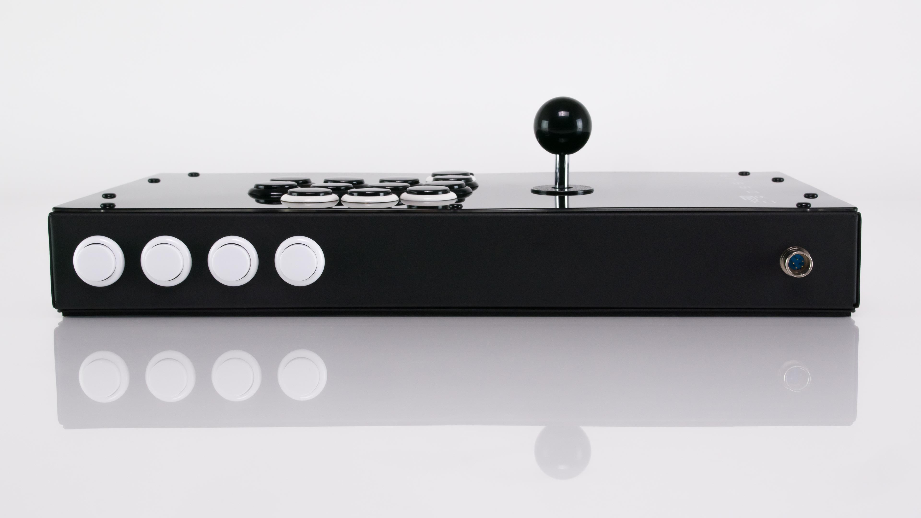 Low front-edge view of the Hit Box Cross|Up showing four side-mounted function buttons and the detachable-cable connector.